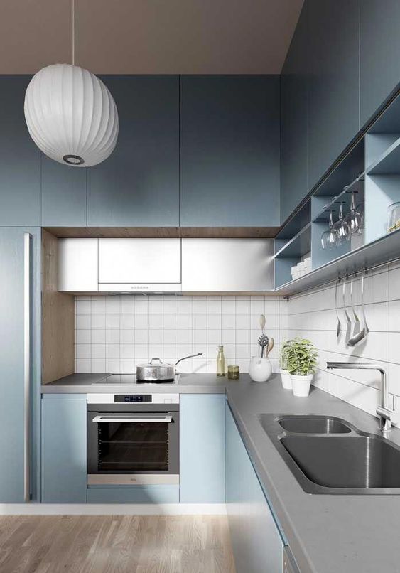 a minimalist light blue kitchen with grey additional cabinets and a concrete countertop plus a white tile backsplash
