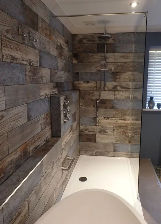 A modern bathroom clad with reclaimed wood look tiles, with white appliances and built in lights is a stylish and cool idea