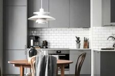 a modern sleek grey kitchen with a white subway tile backsplash and a wooden floor for a cozy touch