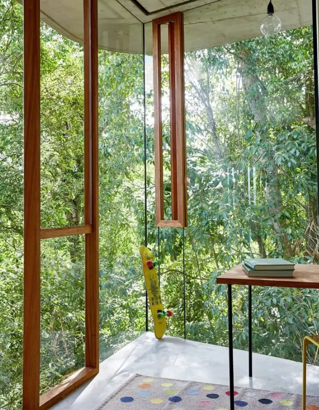 a perfect biophilic home office with glazed walls that allow natural light and a cool woodland view at the same time