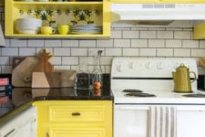 a retro kitchen done in white and yellow, with white appliances and a white subway tile backsplash plus black countertops
