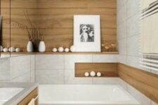 a serene minimalist bathroom clad with neutral large scale tiles and wood look ones, with a wooden vanity, some candles and an artwork