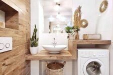 a small boho bathroom clad with wood tiles, with a wooden vanity that includes a washing machine, some potted plants