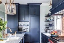 a statement blue kitchen with a marble tile backsplash, stone countertops and catchy pendant lamps and sconces
