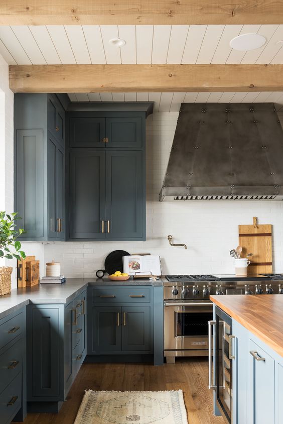 a stylish blue kitchen with stainless steel appliances, touches of natural wood and brass is a super chic and cool space