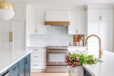 a stylish kitchen with blue kitchen islands, white cabinets and countertops plus chic brass touches