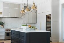 a stylish kitchen with white and dove grey cabinets, a midnight blue kitchen island, elegant gold pendant lamps