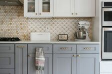 a stylish two-tone kitchen with upper white and lower grey cabinets, a penny and scallop tile backsplash, a bold rug