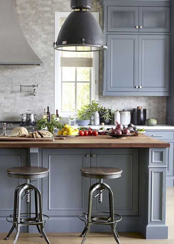 a traditional kitchen in slate blue with a grey tile, butcherblock countertops and vintage furniture and lamps