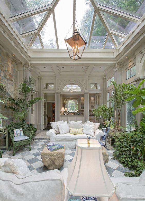 a traditional space done in a biophilic way, with lots of potted plants and a glass ceiling for much natural light and views