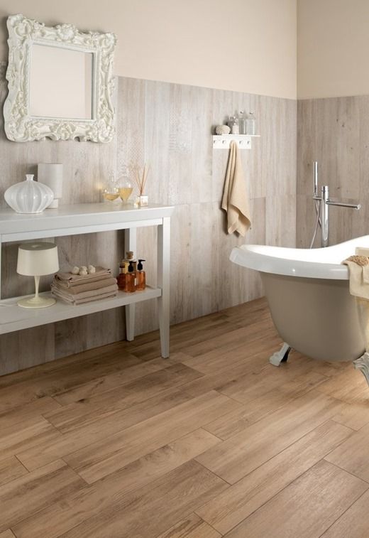A vintage bathroom with wooden floor and wood inspired tiles on the wall, a console table, a clawfoot bathtub