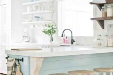 a vintage-inspired coastal kitchen with white cabinets, a light blue kitchen island and matching lamps over it, open shelving and vintage stools
