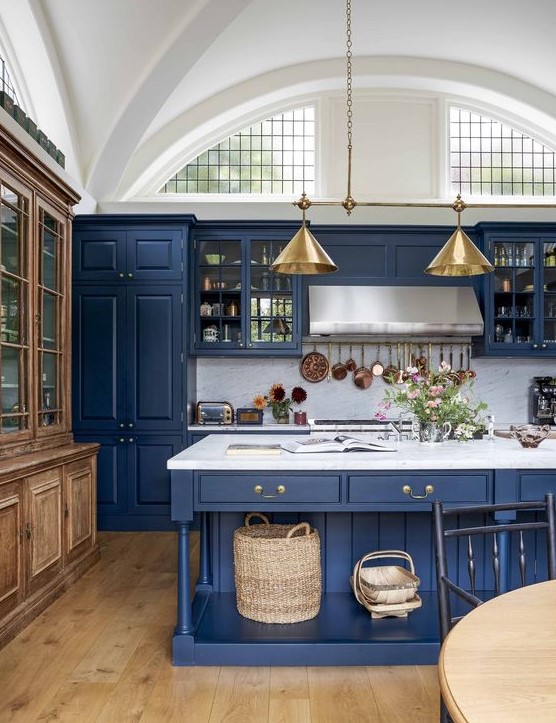 A vintage inspired kitchen in classic blue, with a white marble backsplash and countertos plus gold lamps
