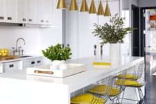 a white kitchen done with slight yellow accents – yellow stools and lemons in a bowl plus gold lamps over the island