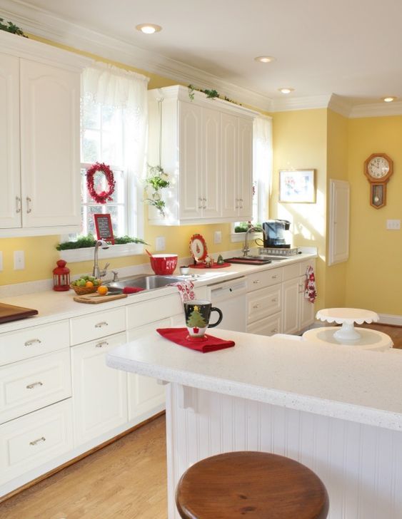 a white vintage kitchen with a sunny yellow backsplash and accent wall, touches of red and fresh greenery