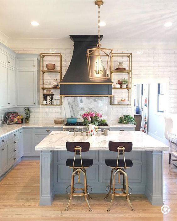an art deco kitchen with powder blue cabinets and a kitchen island completed with a white stone countertop and a tile backsplash