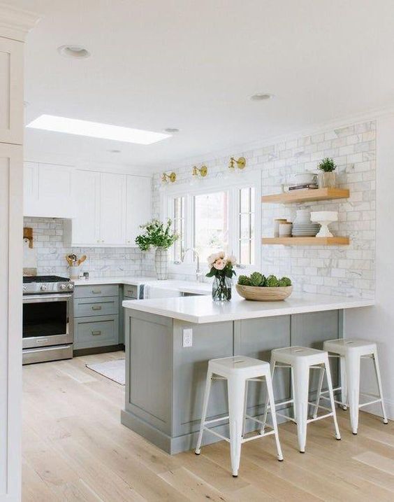 an ethereal kitchen with dove grey lower cabinets, white upper ones, white countertops and tile walls plus touches of gold