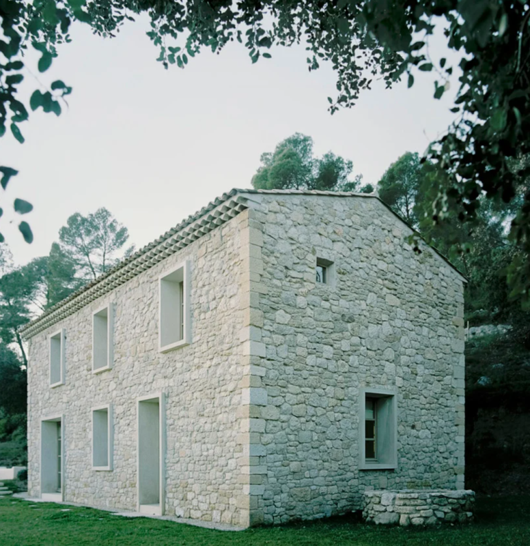 The house resembles a stone barn, there are many windows to bring light in and glazed doors