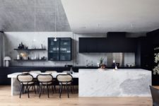 02 The kitchen is done with sleek black cabinets, a white marble kitchen island and chic chairs