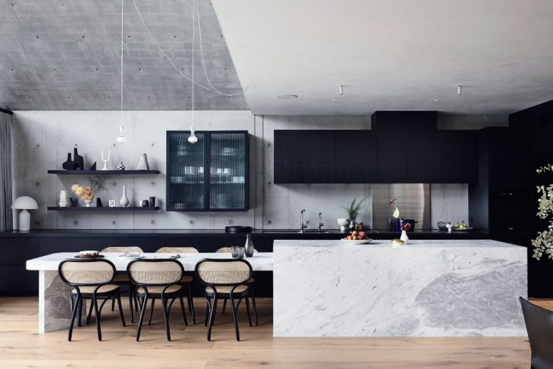 The kitchen is done with sleek black cabinets, a white marble kitchen island and chic chairs