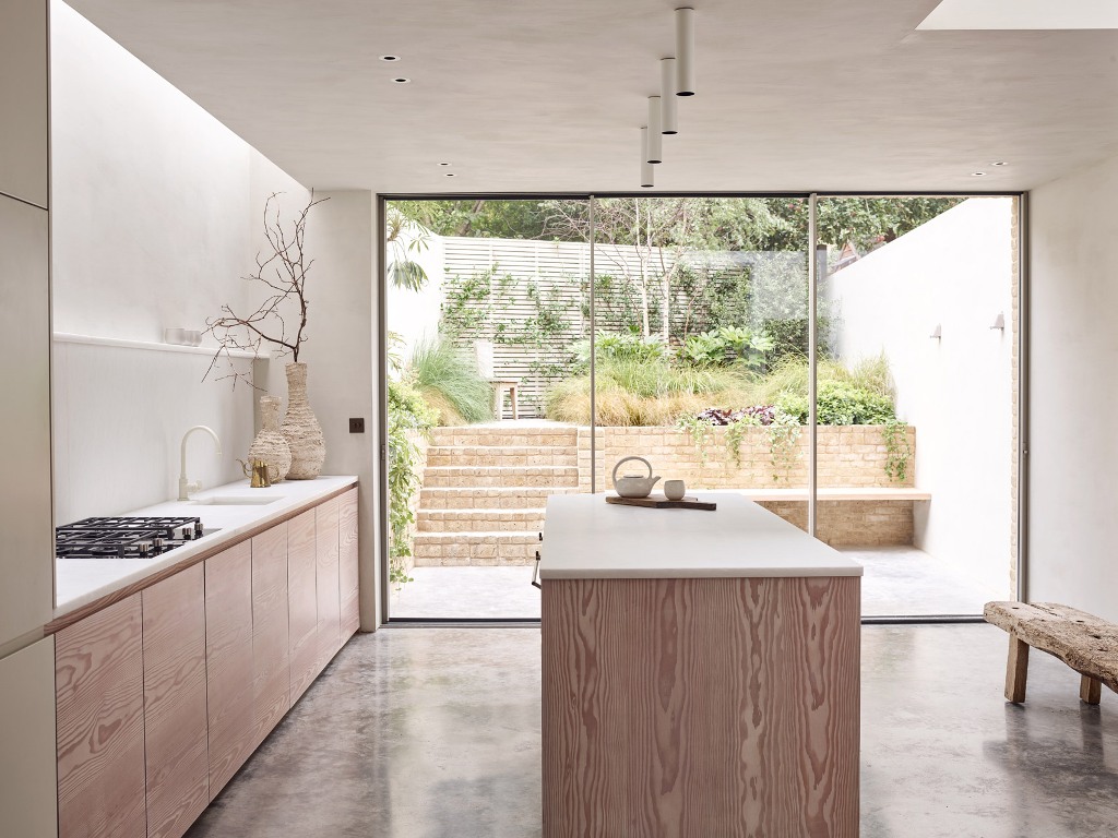 The kitchen is peaceful and neutral, the cabinets are only lower ones, lots of white surfaces create a calm feel, and a glazed door brings much natural light