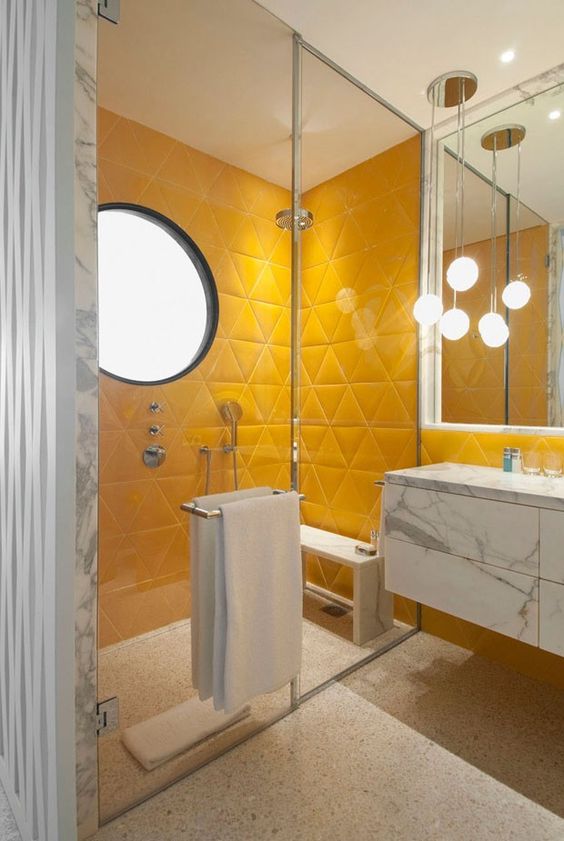 a bright bathroom in sunny yellow, with a marble floating vanity, a terrazzo floor and cool pendant lamps