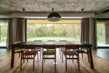 05 The dining space is placed in front of the window, with colorful chairs and a concrete ceiling that contrasts the warm decor