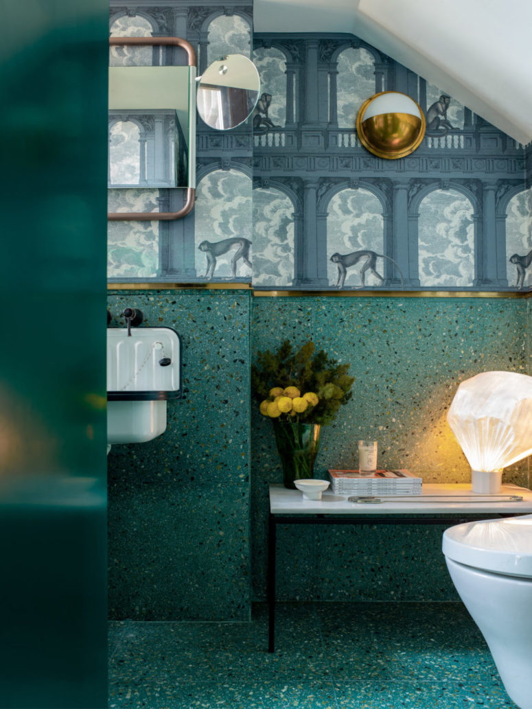 The bathroom continues with the colors of the apartment - teal and deep green and surprises with catchy wallpaper