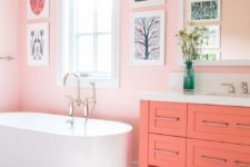 06 a pink bathroom with pink walls, a coral vanity, a bright printed rug and a fun gallery wall is a very whimsy space