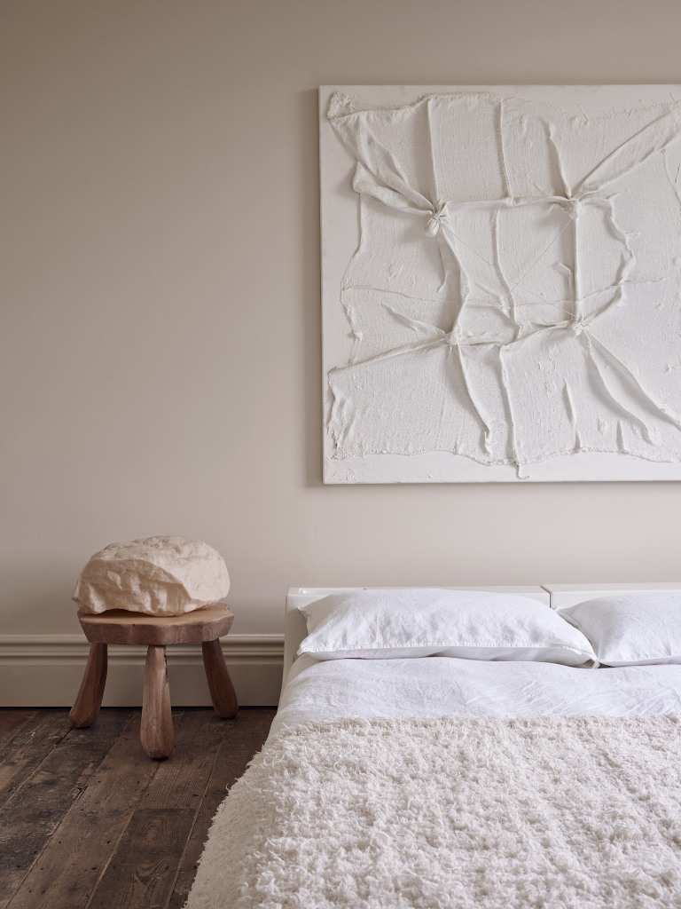 The bedroom is done with neutral walls, simple furniture and a very catchy piece of art