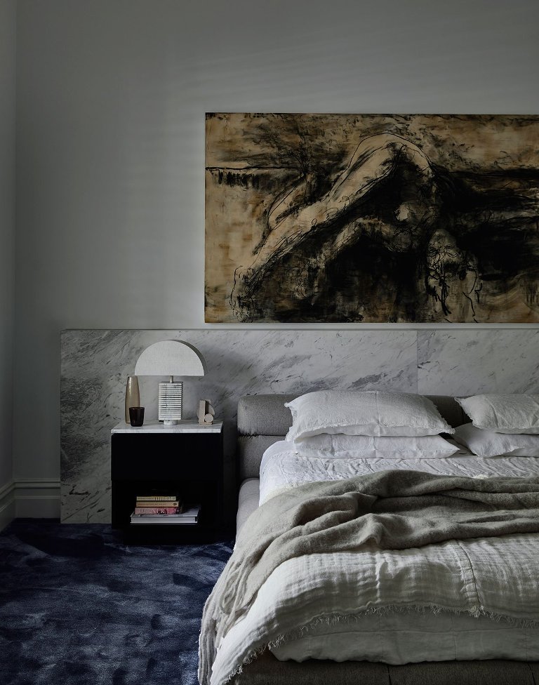 The master bedroom is done with stone, a catchy artwork and a brushstroke rug