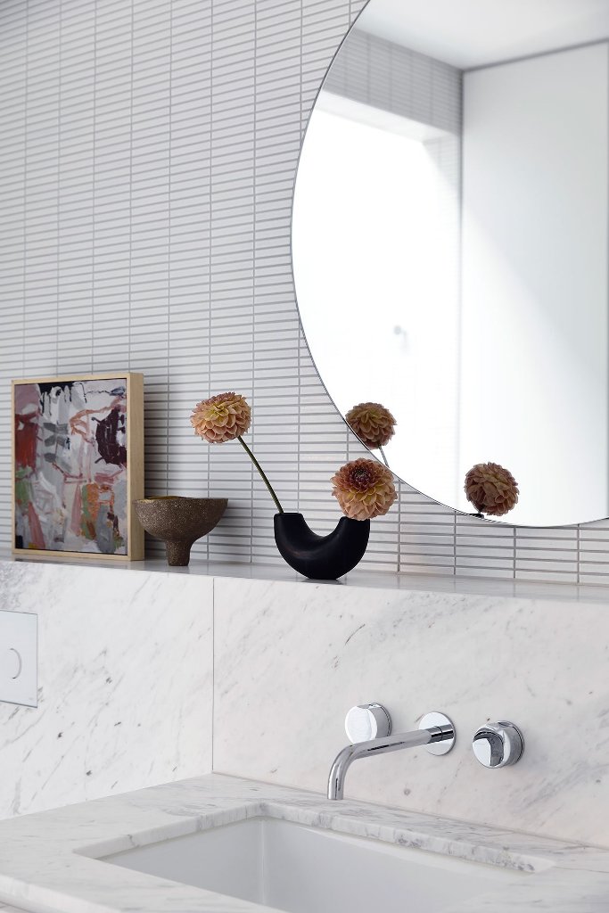 The bathroom is contemporary and neutral, done with large stone tiles and some usual smaller ones