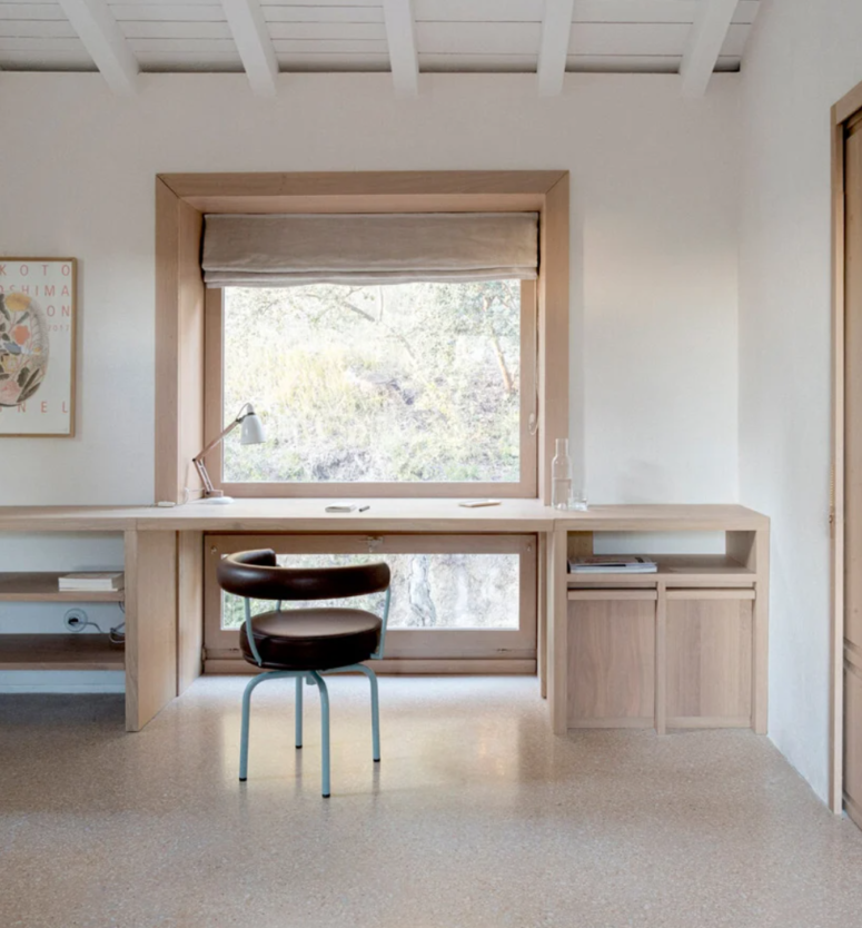 The home office continues the kitchen style, with a plywood desk, storage and a window frame plus a leather chair