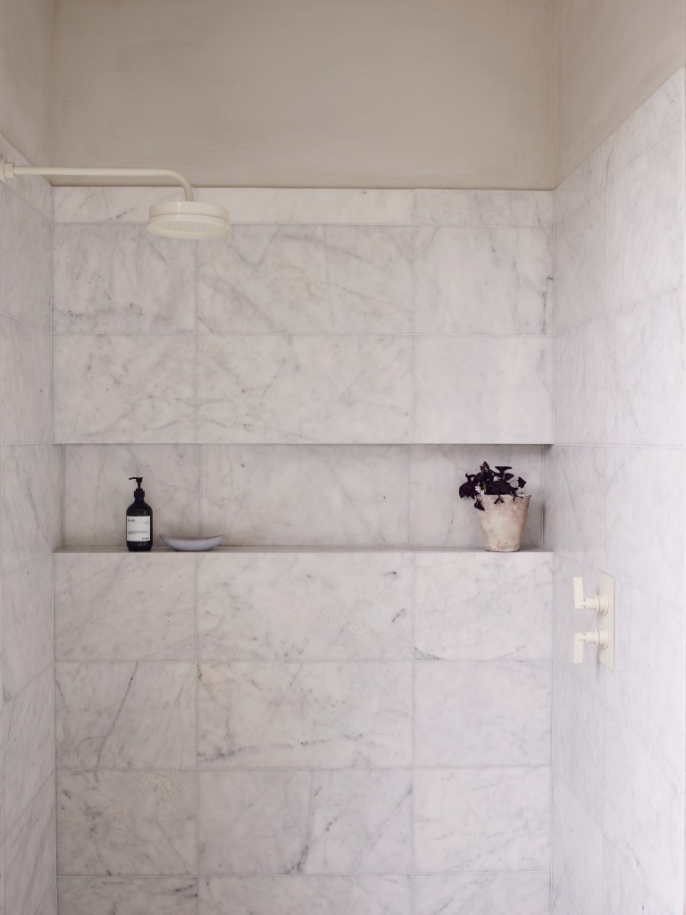 The small bathroom features a shower space clad with white marble tiles