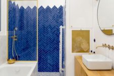 09 a bold bathroom with electric blue tiles, a dolmatin tile floor, a bold wooden vanity and a matching cover plus touches of gold