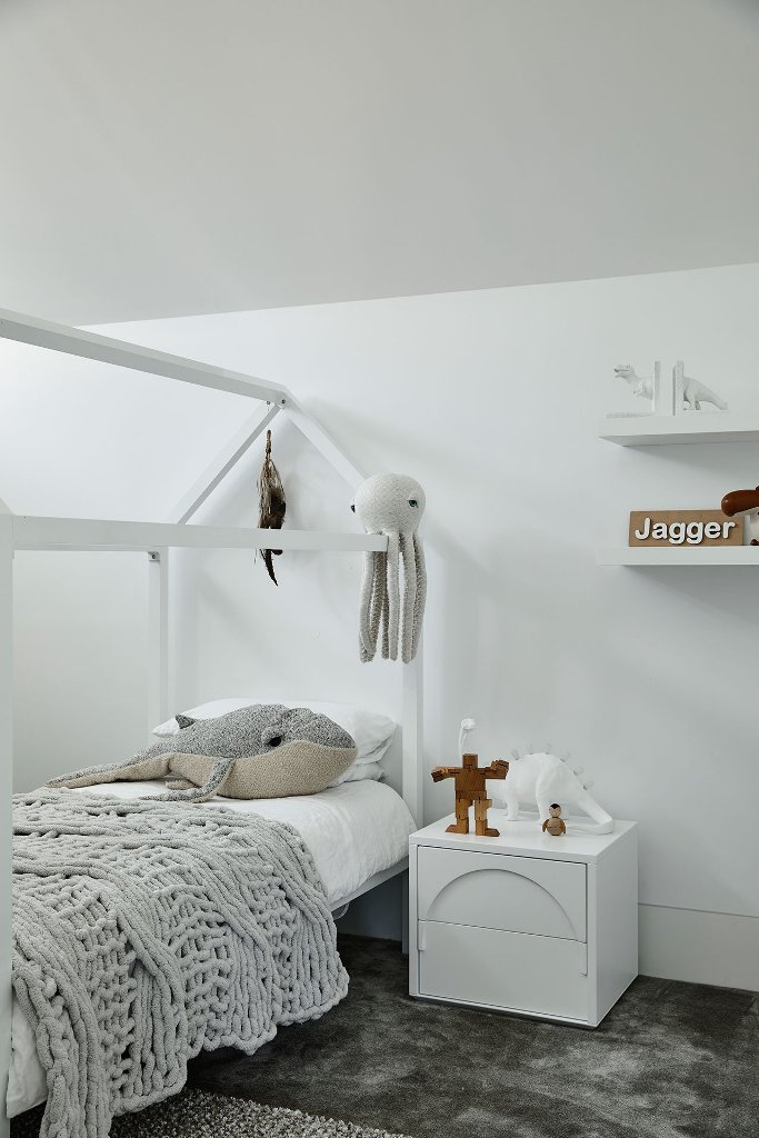 Another kid bedroom is also white, with a house shaped bed and fun toys all around