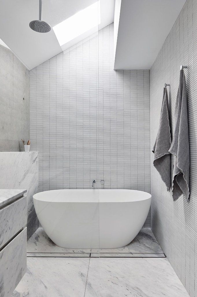 The bathroom features a skylight and a cool bathtub-shower space
