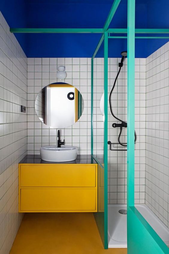 a bold modern bathroom with a bold blue ceiling, a yellow vanity and turquoise frames and half walls