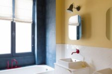 18 a colorful bathroom with yellow walls, a yellow and white mosaic floor and navy tiles around the bathtub plus fuchsia fixtures