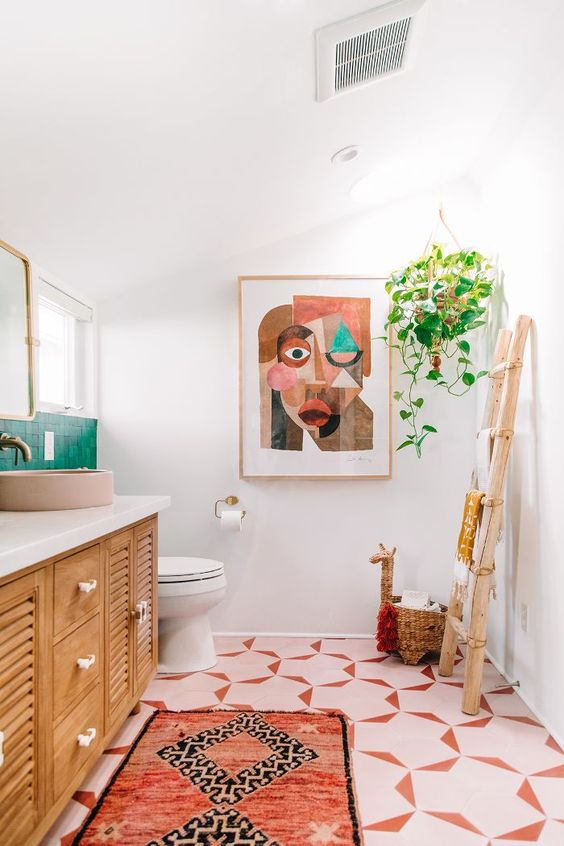 a colorful space with an emerald tile backsplash, pink sinks and lamps and a bright boho rug