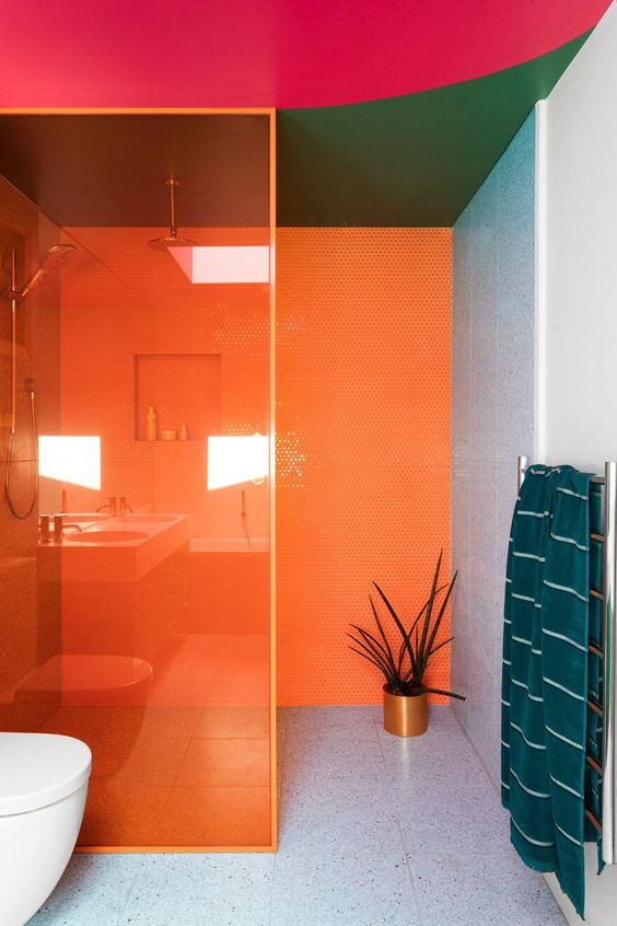a modernist bathroom in bold orange, green, pink and grey plus teal textiles is a super colorful space