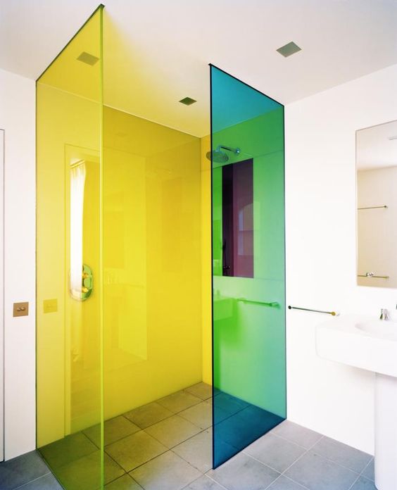 a white bathroom with green and yellow florescent glass shower doors that take over this space