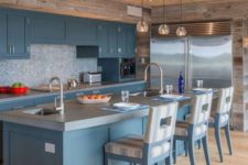 a beautiful blue kitchen with a mosaic backsplash, a concrete countertop, a wooden ceiling and reclaimed wood on the walls