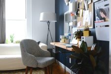 a bright and eclectic home office with a navy statement wall, a bright wlal with art and a pegboard, catchy furniture and a bold rug