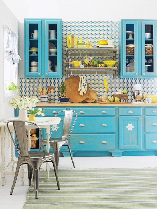 a bright blue kitchen with a bright mosaic tile backsplash and bold touches of yellow here and there is super cool