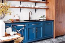 a bright blue kitchen with black countertops, rich stained wooden shelves and a buffet plus a dining set