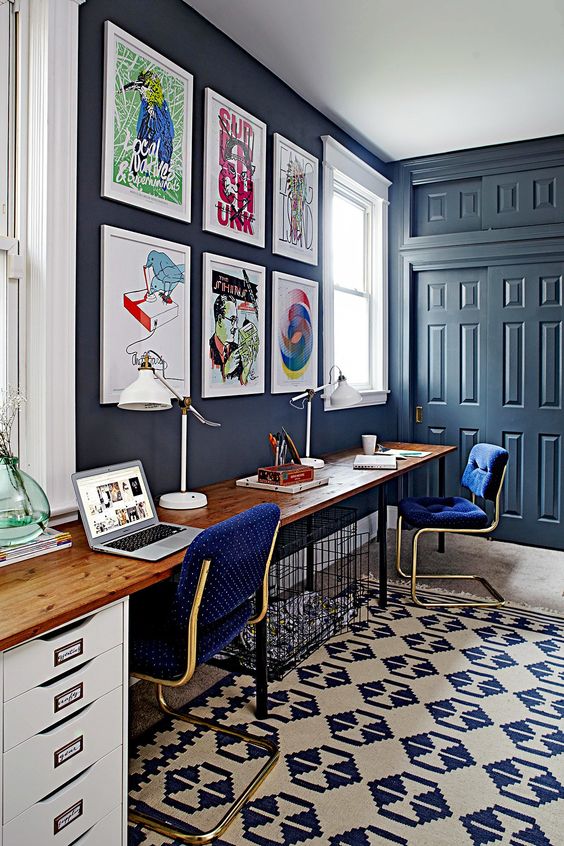 a bright home office with navy walls and doors, bright polka dot chairs and a crazy gallery wall and a printed rug