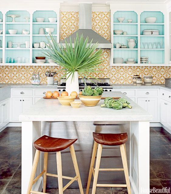 a bright tropical kitchen with a bold yellow tile backsplash, turquoise cabinets and touches of fresh greenery
