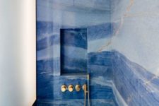 a catchy and bold blue bathroom done with watercolor tiles, gold fixtures and lamps is a stylish space