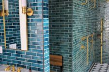 a catchy bathroom clad with blue tiles, finished off with gold fixtures and sconces looks wow